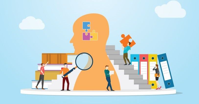 Against a light-blue background with floating clouds, a team of small people work around a large head, searching for information, loading knowledge from books, and carrying information in the shape of puzzle pieces into the brain.